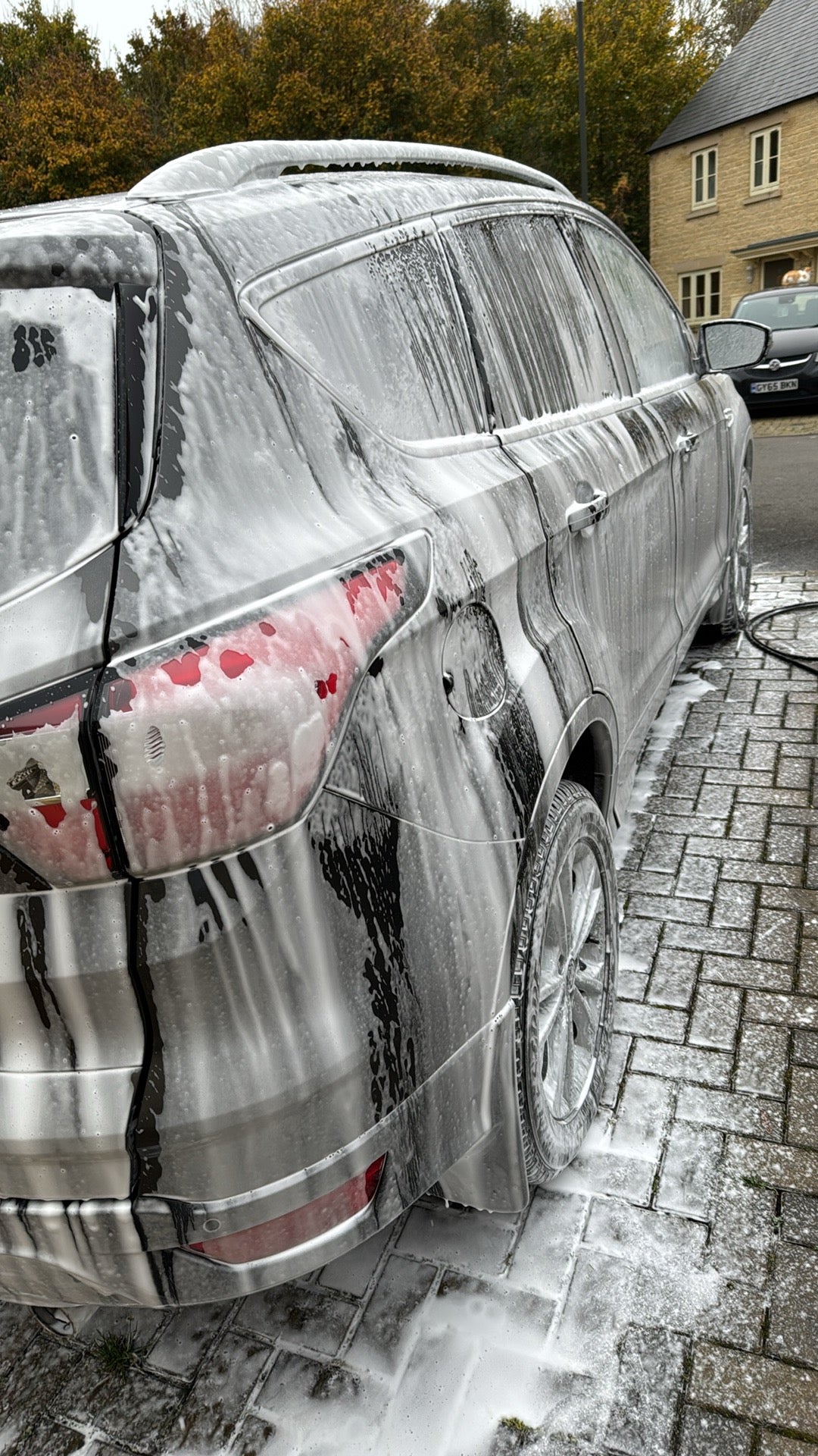 Car covered in thick foam during washing process using Lycan Auto Care snow foam for a deep clean